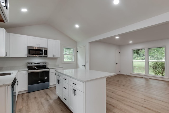 kitchen with a kitchen island, white cabinetry, appliances with stainless steel finishes, and light hardwood / wood-style flooring