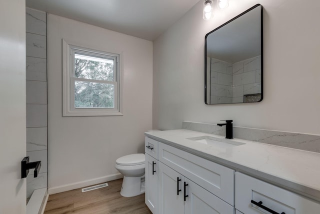 bathroom featuring wood-type flooring, toilet, and vanity