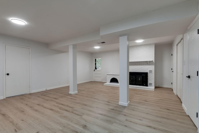 basement with a fireplace and light hardwood / wood-style floors