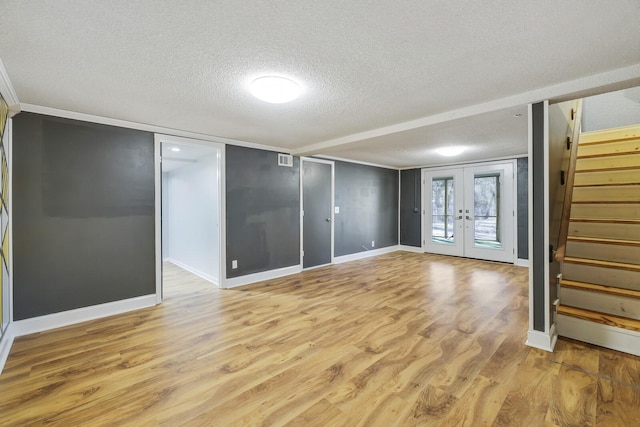 empty room featuring a textured ceiling, light hardwood / wood-style floors, and french doors