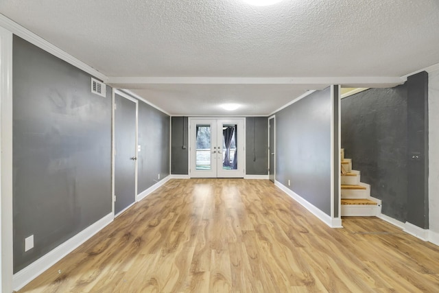 basement featuring french doors, crown molding, light hardwood / wood-style floors, and a textured ceiling