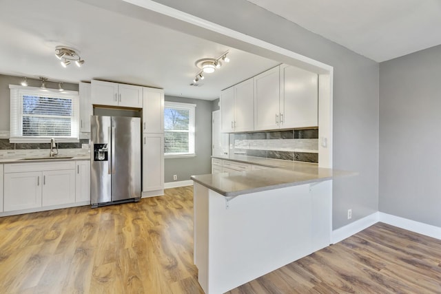 kitchen with white cabinetry, sink, kitchen peninsula, and stainless steel fridge with ice dispenser