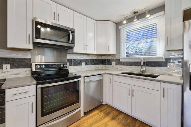 kitchen with tasteful backsplash, appliances with stainless steel finishes, sink, and white cabinets