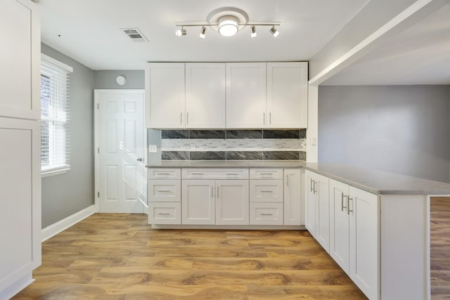 kitchen with white cabinetry, tasteful backsplash, kitchen peninsula, and light hardwood / wood-style flooring