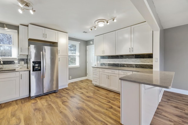 kitchen with stainless steel fridge with ice dispenser, a kitchen breakfast bar, white cabinets, and light wood-type flooring