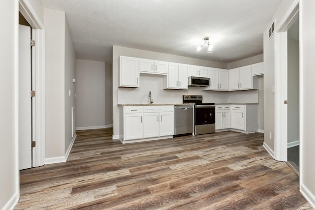 kitchen with stainless steel appliances, dark hardwood / wood-style floors, sink, and white cabinets