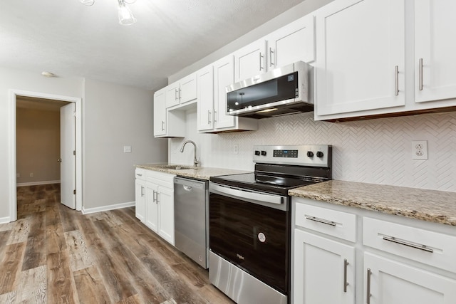 kitchen with tasteful backsplash, appliances with stainless steel finishes, sink, and white cabinets