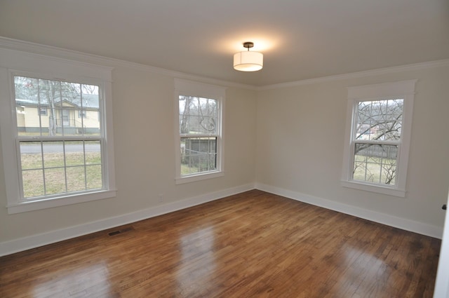 empty room featuring ornamental molding, plenty of natural light, and dark hardwood / wood-style flooring