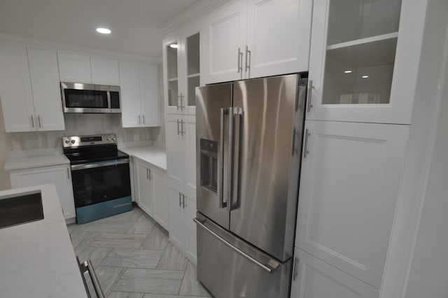 kitchen featuring sink, light stone counters, white cabinets, stainless steel appliances, and backsplash