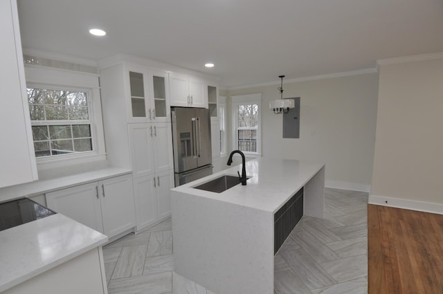 kitchen with pendant lighting, white cabinetry, sink, high end refrigerator, and a center island with sink