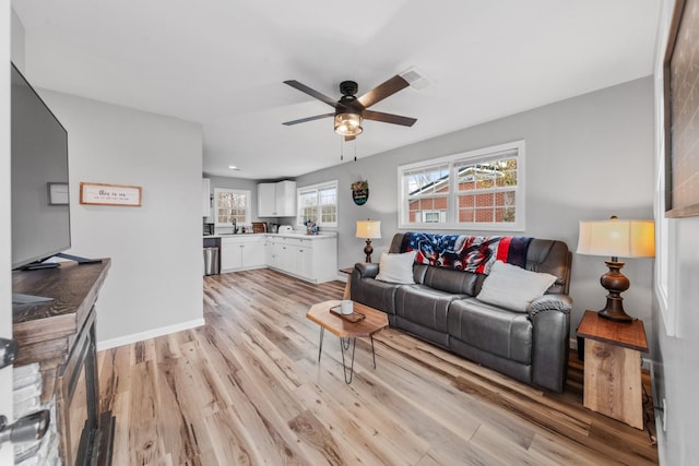 living room with sink, ceiling fan, and light wood-type flooring