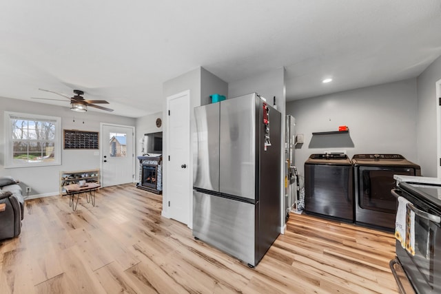 kitchen featuring a fireplace, stainless steel appliances, washing machine and dryer, and light wood-type flooring