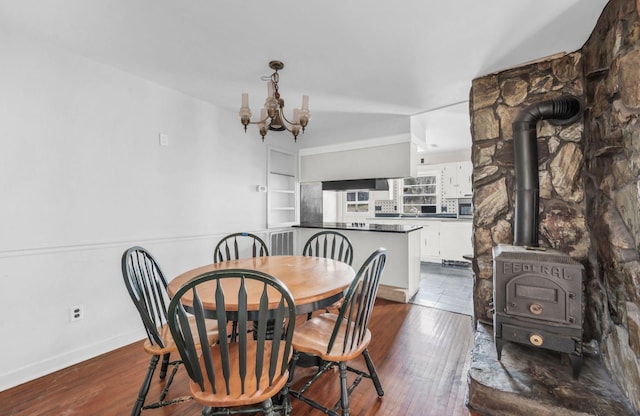 dining room featuring a notable chandelier, dark hardwood / wood-style flooring, and a wood stove