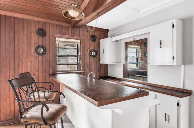 kitchen featuring wood walls, a breakfast bar, and white cabinets