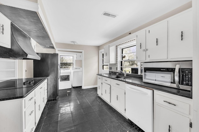 kitchen with sink, appliances with stainless steel finishes, white cabinetry, independent washer and dryer, and a healthy amount of sunlight