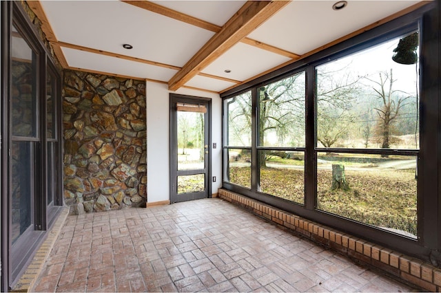 unfurnished sunroom featuring beam ceiling