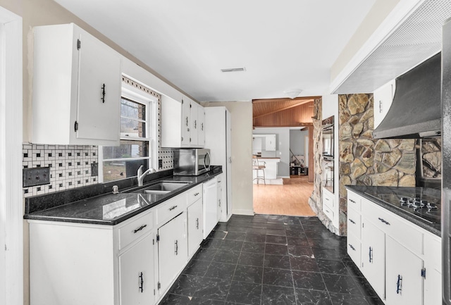 kitchen with sink, white cabinetry, tasteful backsplash, black electric cooktop, and dark stone counters