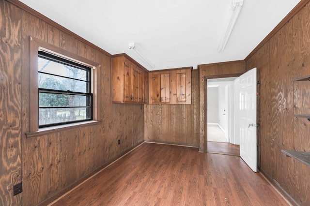 unfurnished bedroom with wooden walls, ornamental molding, and dark hardwood / wood-style flooring