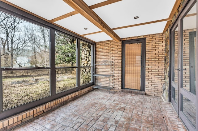 unfurnished sunroom with beamed ceiling and a healthy amount of sunlight