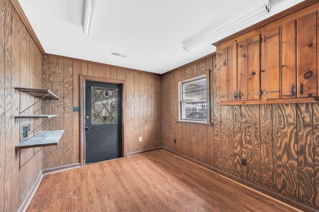 entryway with crown molding, wood-type flooring, and wooden walls