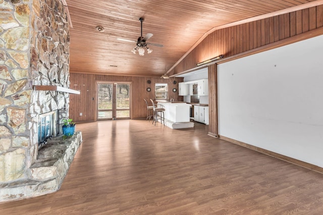 unfurnished living room featuring a stone fireplace, wood walls, wood ceiling, vaulted ceiling, and hardwood / wood-style flooring