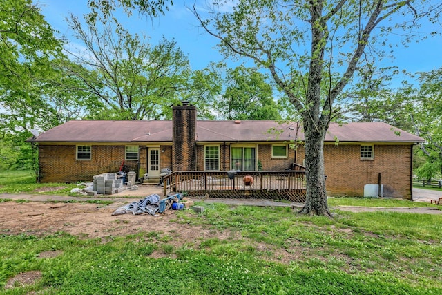 rear view of property featuring a patio area, a wooden deck, a chimney, and brick siding