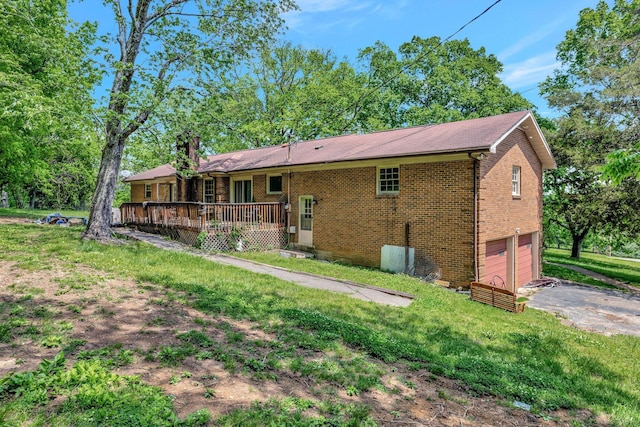 back of house featuring a garage, a chimney, a deck, brick siding, and driveway