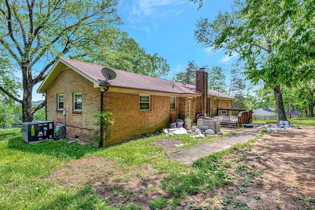 rear view of property with a chimney, brick siding, crawl space, central AC unit, and a deck