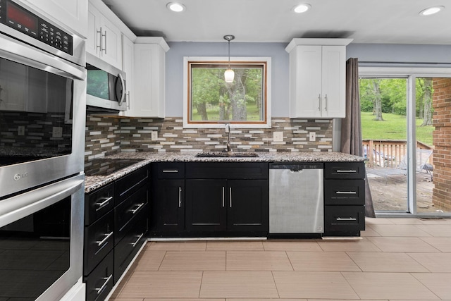 kitchen featuring white cabinets, stainless steel appliances, dark cabinetry, and a sink