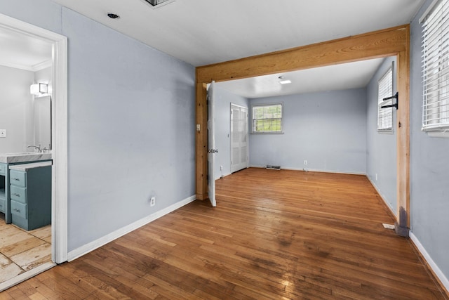 spare room featuring crown molding, wood-type flooring, and baseboards