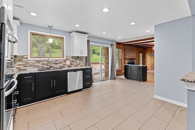 kitchen with dishwasher, dark cabinets, a sink, backsplash, and white cabinets