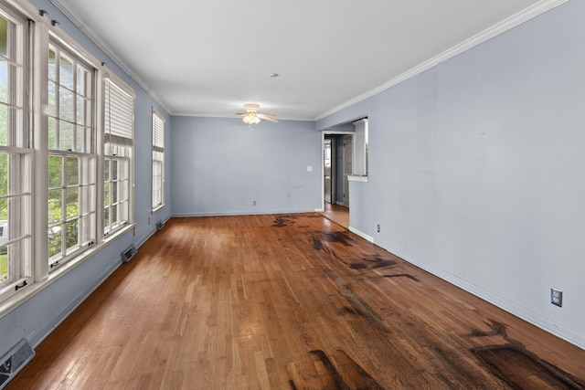 empty room featuring a ceiling fan, baseboards, visible vents, crown molding, and hardwood / wood-style flooring