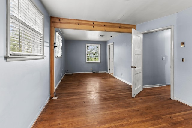 spare room with baseboards and wood finished floors