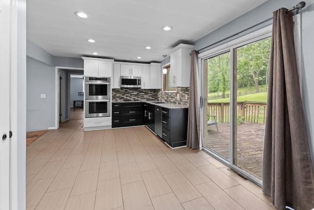 kitchen featuring recessed lighting, a sink, white cabinetry, backsplash, and stainless steel appliances