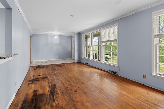 unfurnished room featuring baseboards, ornamental molding, wood-type flooring, and visible vents