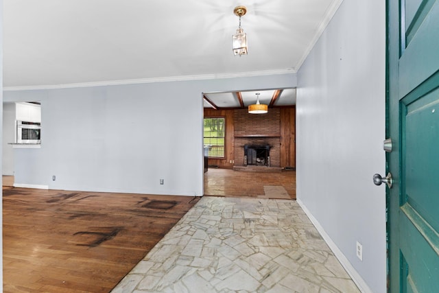 foyer with crown molding, a brick fireplace, and baseboards