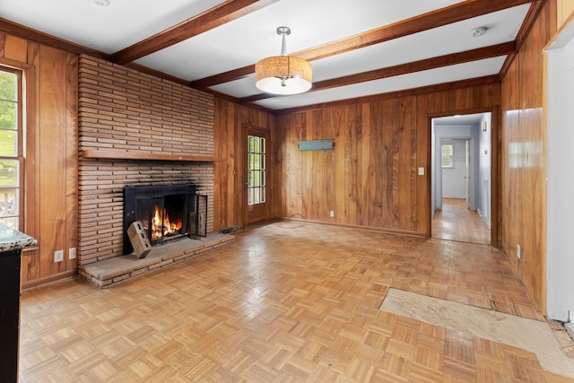 unfurnished living room with baseboards, wooden walls, and beam ceiling