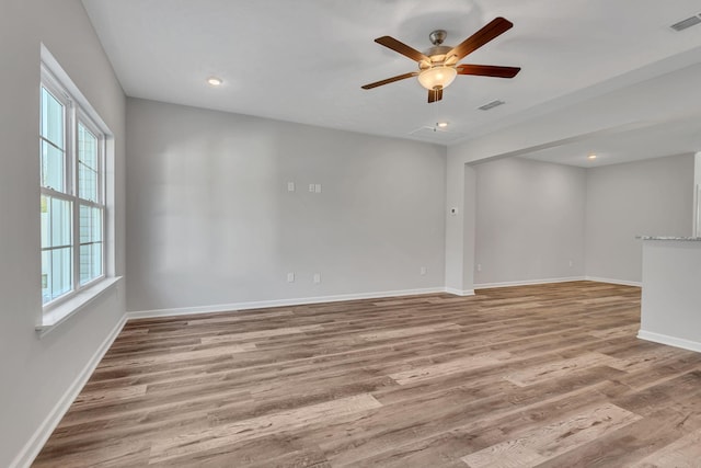 empty room featuring light wood finished floors, a ceiling fan, visible vents, and baseboards