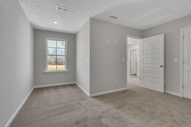 unfurnished room with baseboards, attic access, visible vents, and light colored carpet