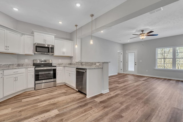 kitchen featuring stainless steel appliances, visible vents, hanging light fixtures, open floor plan, and white cabinetry