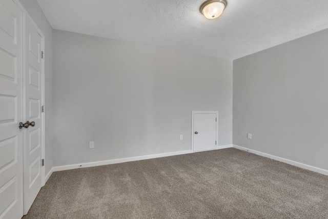 empty room with carpet floors, baseboards, and a textured ceiling