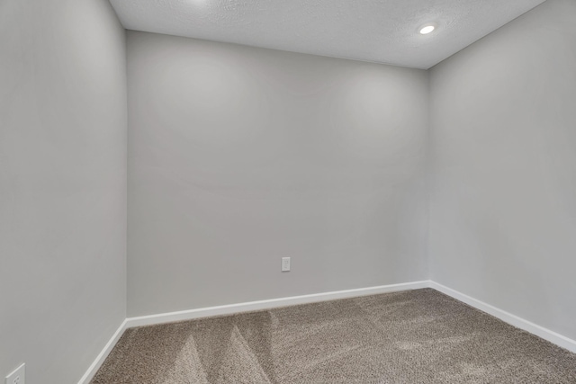 carpeted spare room featuring baseboards and a textured ceiling