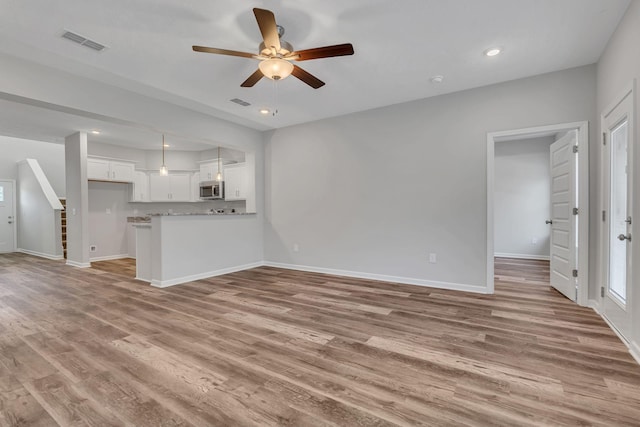 unfurnished living room featuring light wood finished floors, recessed lighting, visible vents, stairway, and baseboards