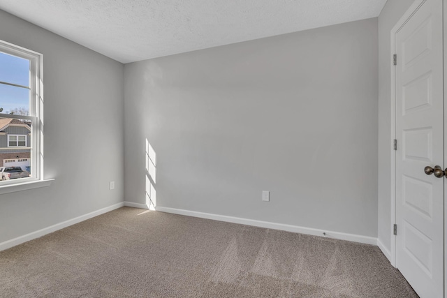 carpeted spare room featuring a textured ceiling and baseboards