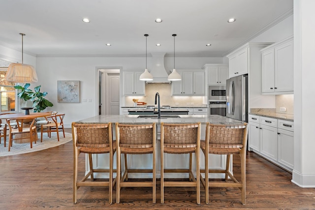 kitchen featuring white cabinetry, appliances with stainless steel finishes, a center island with sink, and pendant lighting