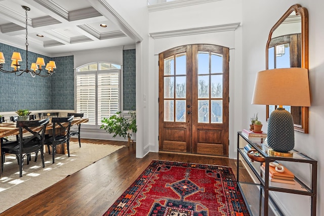 entryway with ornamental molding, coffered ceiling, a notable chandelier, dark wood-type flooring, and french doors