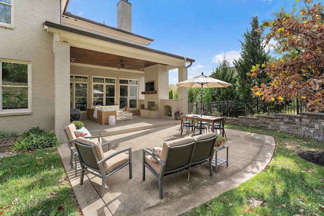 view of patio / terrace with ceiling fan and an outdoor living space with a fireplace