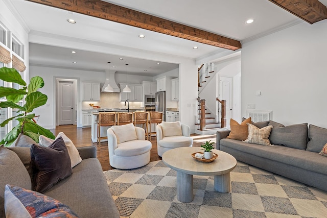 living room featuring ornamental molding, sink, hardwood / wood-style floors, and beam ceiling