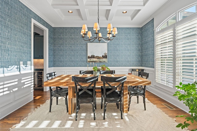 dining area with coffered ceiling, an inviting chandelier, ornamental molding, beam ceiling, and hardwood / wood-style floors