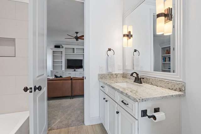 bathroom with a tub to relax in, ceiling fan, and vanity